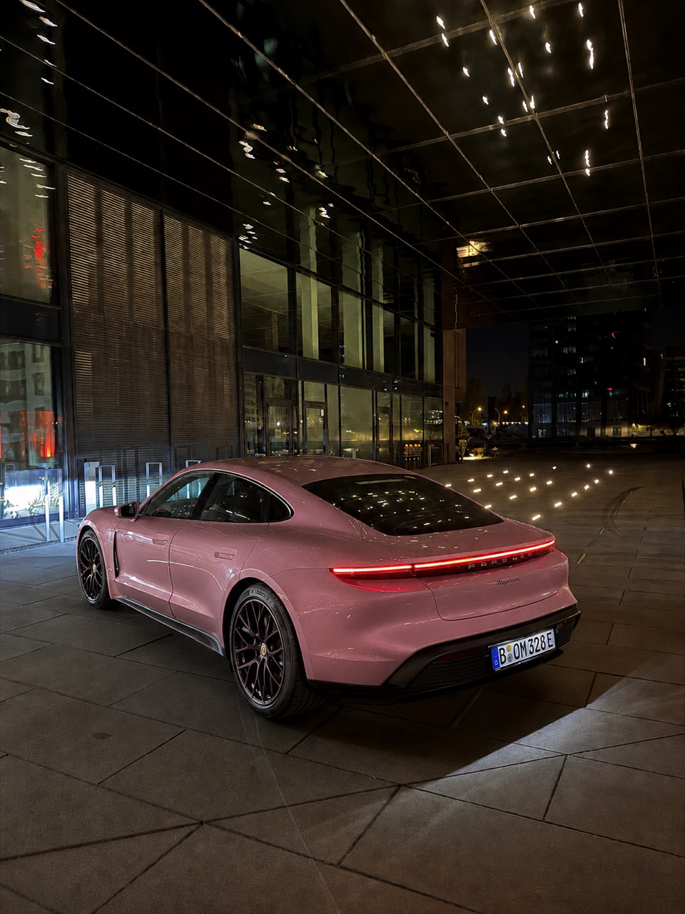 Pinkfarbener Porsche Taycan in einer beleuchteten Nachtkulisse